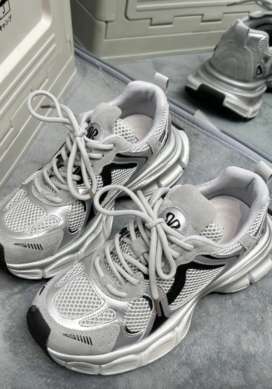 Pair of silver and black mesh chunky running sneakers with suede-style overlays shown in a top-down flat lay