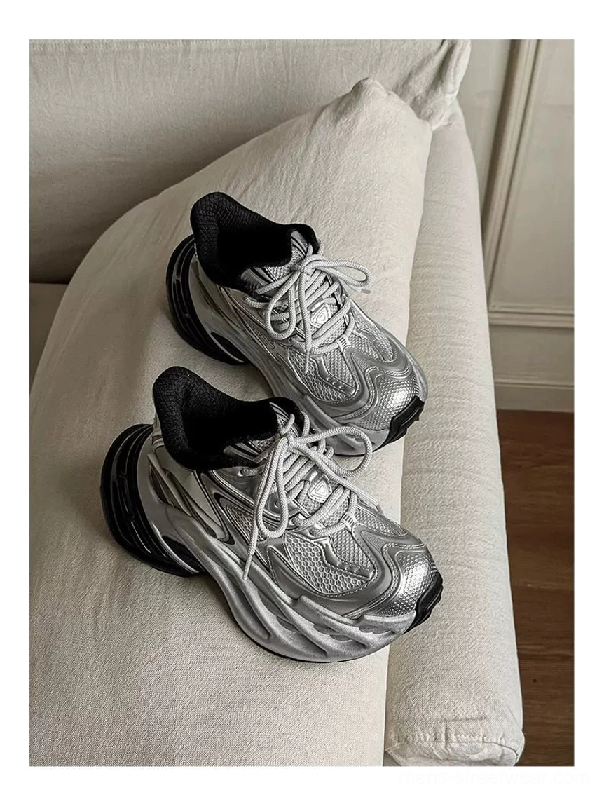 Silver metallic mesh platform runner sneakers with black collar lining and thick outsole on a beige sofa
