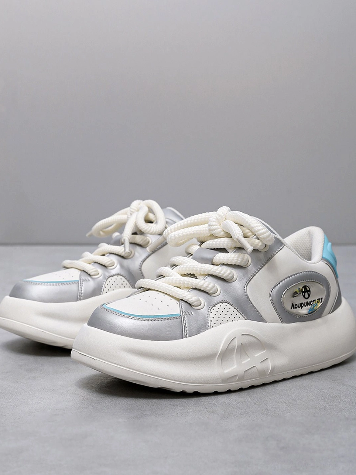Pair of silver metallic PU platform sneakers displayed from the front on a grey background with silver-white-blue color accents