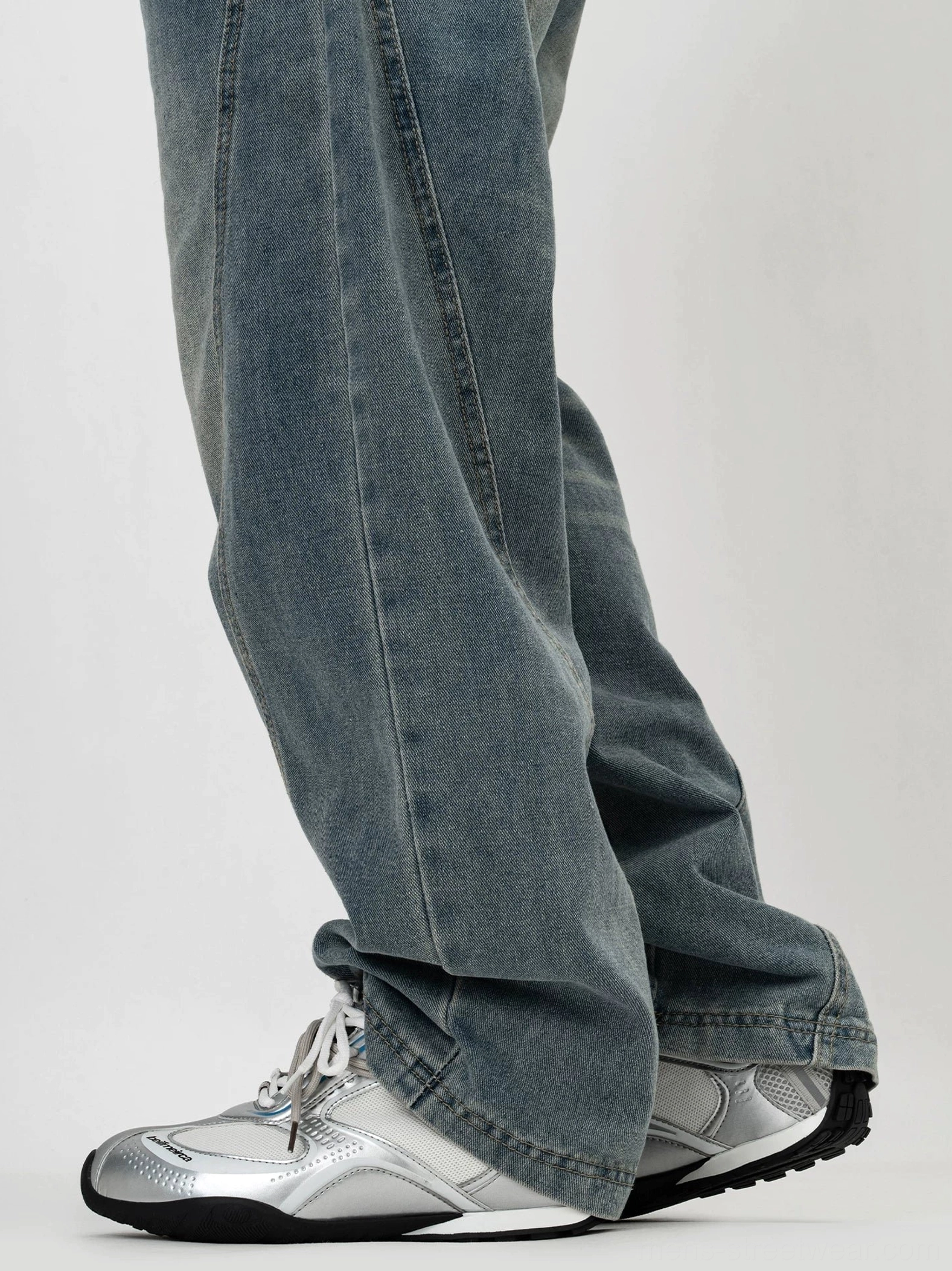 Silver white low top retro running sneakers worn with blue washed jeans showing streamlined mesh upper and snug ankle fit