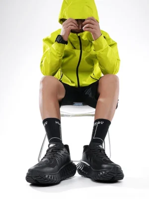 Black chunky streetwear running sneakers worn with crew socks, black shorts and neon yellow outerwear