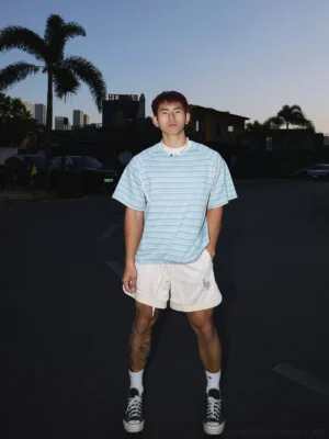Full body outfit featuring light blue striped raglan streetwear tee with white athletic shorts and black canvas sneakers