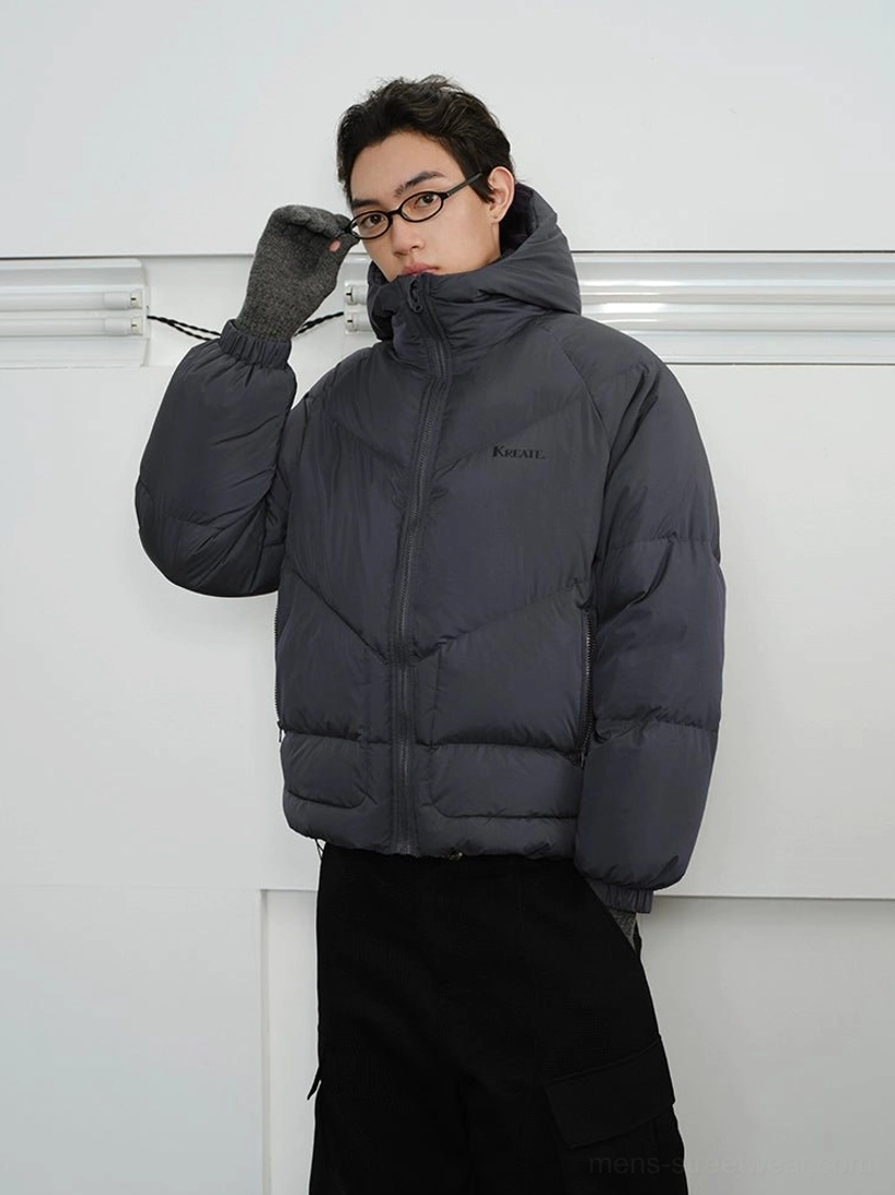 Men's slate grey hooded puffer jacket three-quarter front view showing relaxed cropped fit ribbed cuffs and chevron quilting