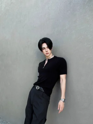Three-quarter view of a slim black ribbed half-zip knit tee styled with black trousers and a leather belt