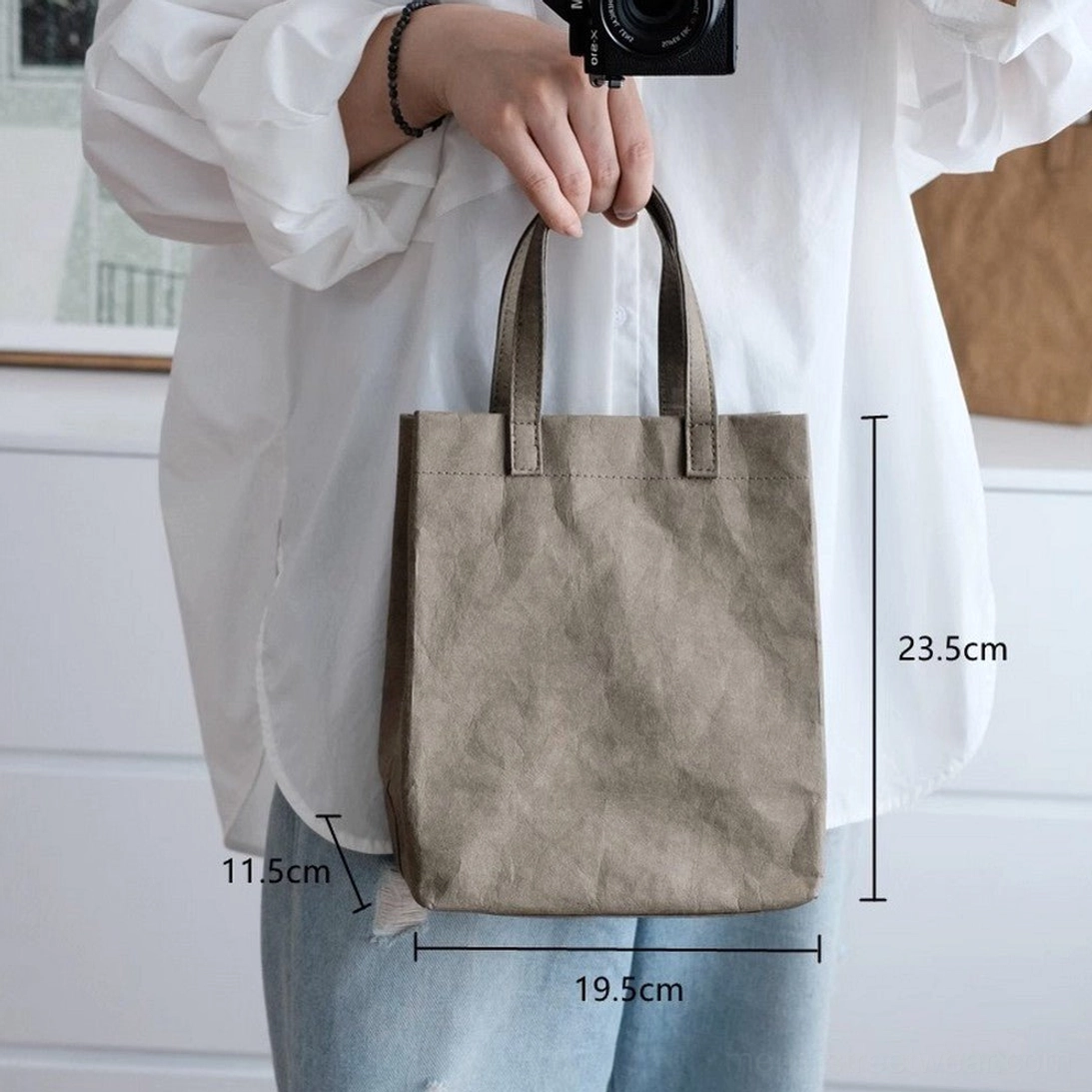 Small army green faux kraft paper texture cotton tote bag worn at waist level showing compact daily carry size