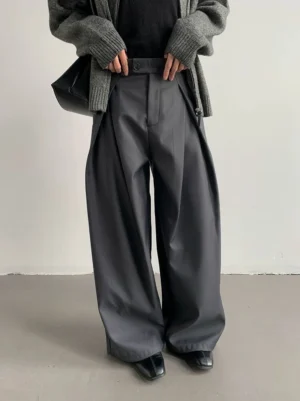 Smoke gray pleated wide-leg draped trousers shown from a low front angle with a black top gray cardigan leather shoes and black handbag