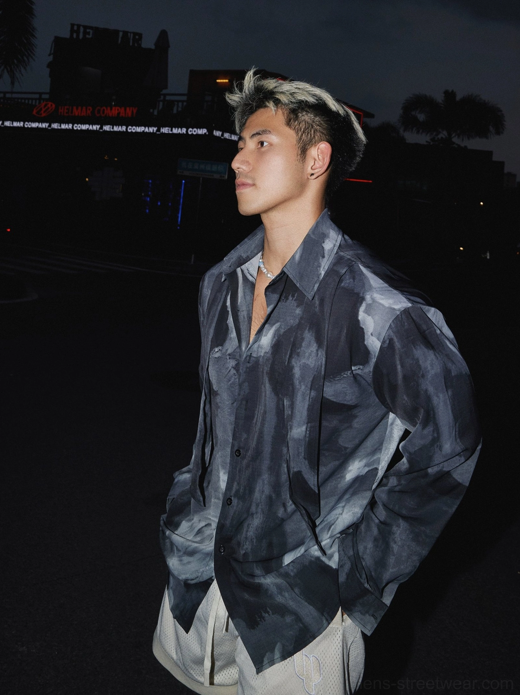Side profile of a male model wearing a smoky monochrome abstract satin oversized shirt with relaxed long sleeves and open neckline
