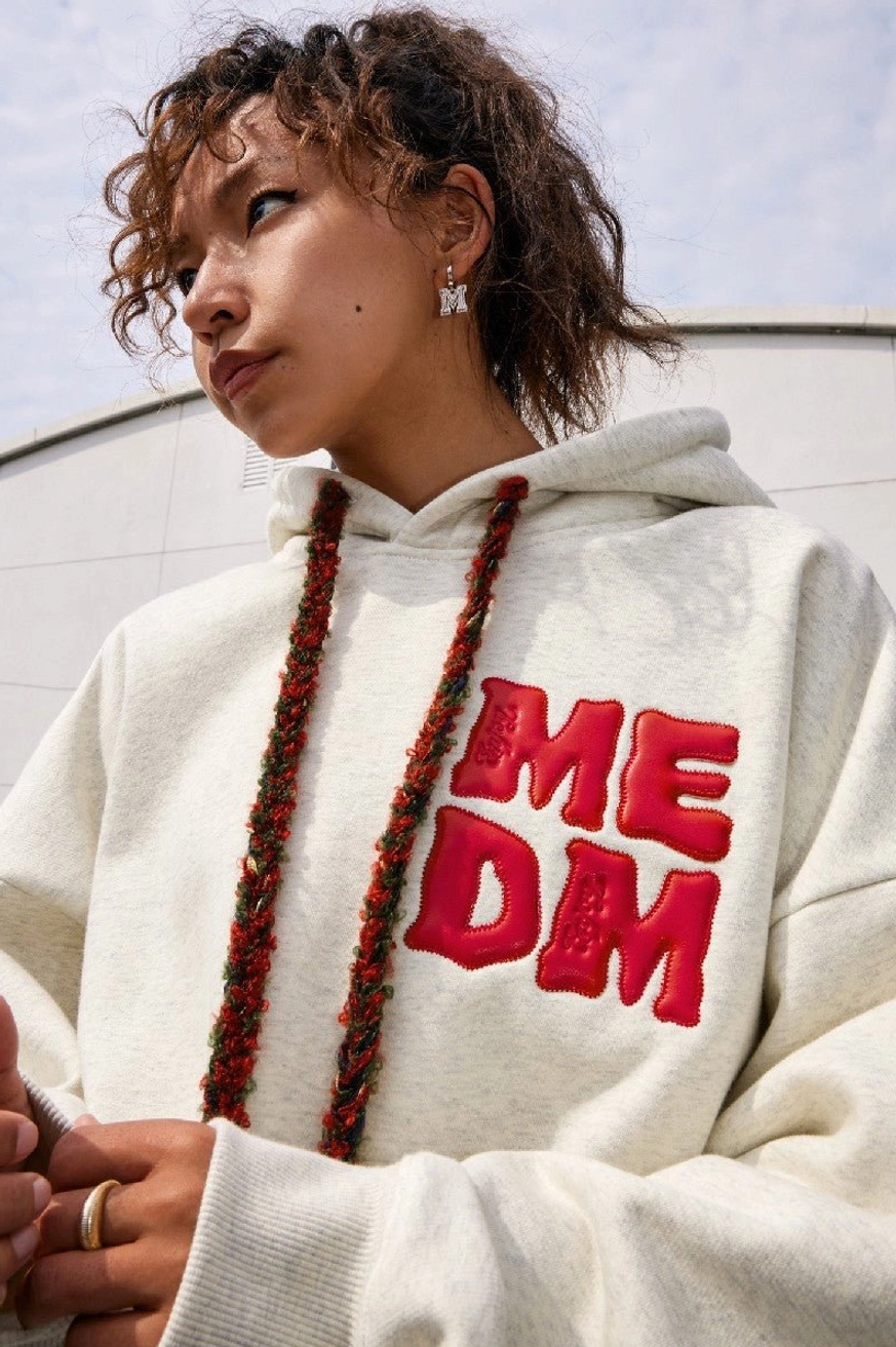 Close-up side view of snowflake gray oversized streetwear hoodie with raised red lettering, two-tone drawstrings, and relaxed fit