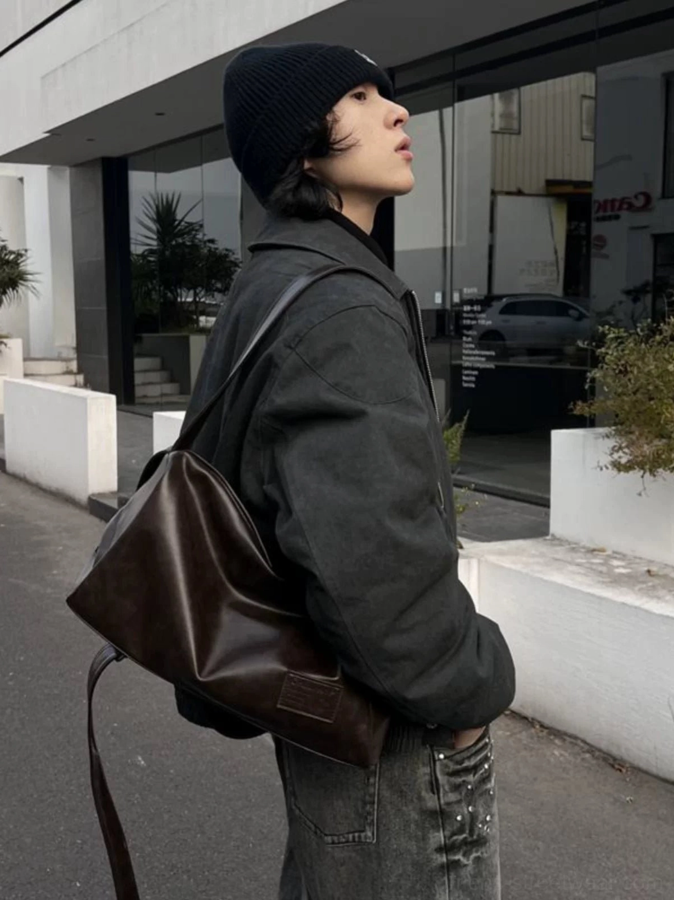 Soft brown PU leather sling bag worn crossbody at the side with a black beanie, utility jacket, and jeans
