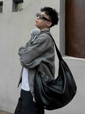 Black Soft Drape Luna Hobo bag worn on a male model in a gray jacket, showcasing the slouchy Korean streetwear shoulder bag silhouette and wide strap