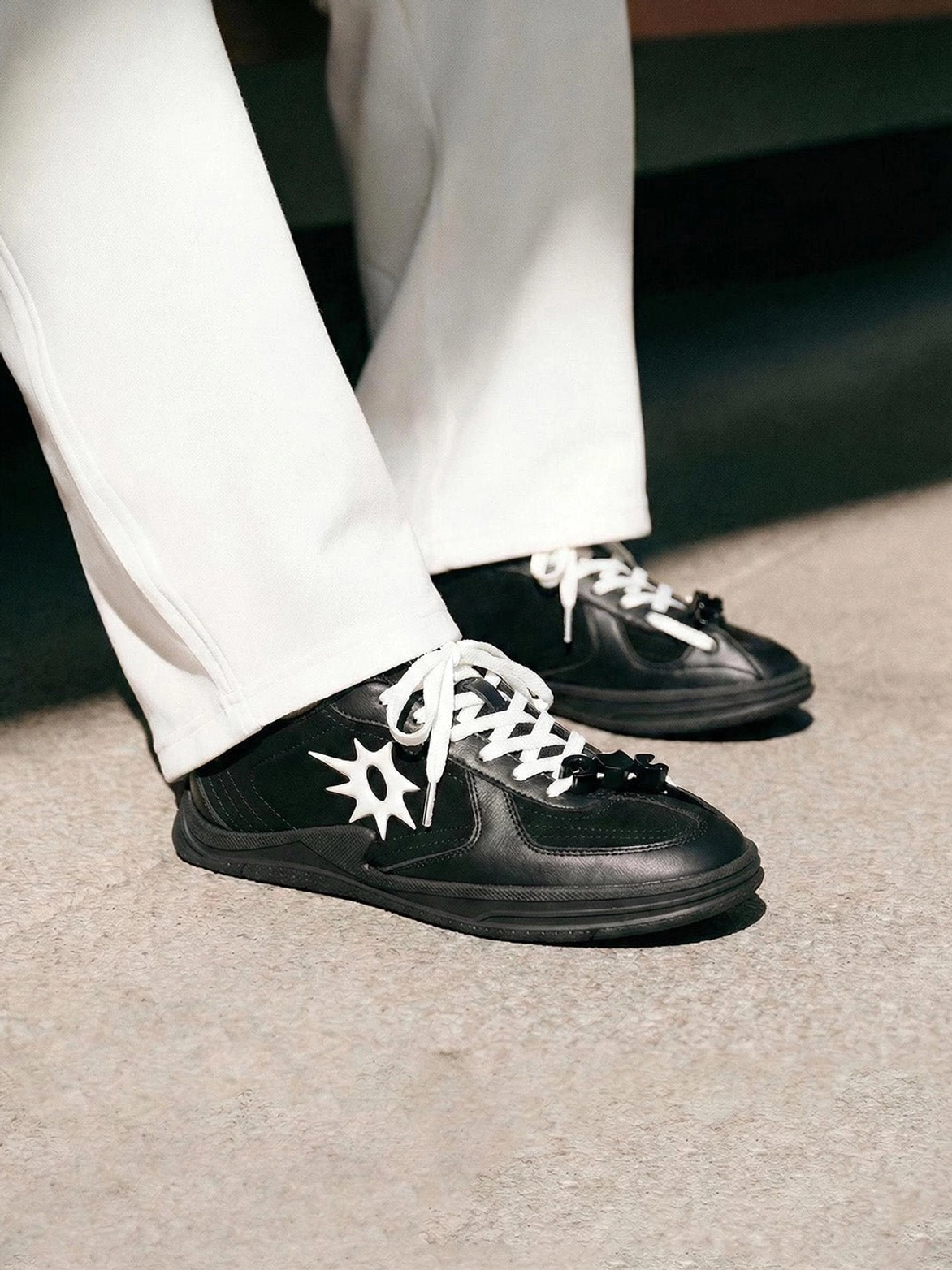 Black and white star applique court sneakers worn with white tailored trousers for a smart casual outfit