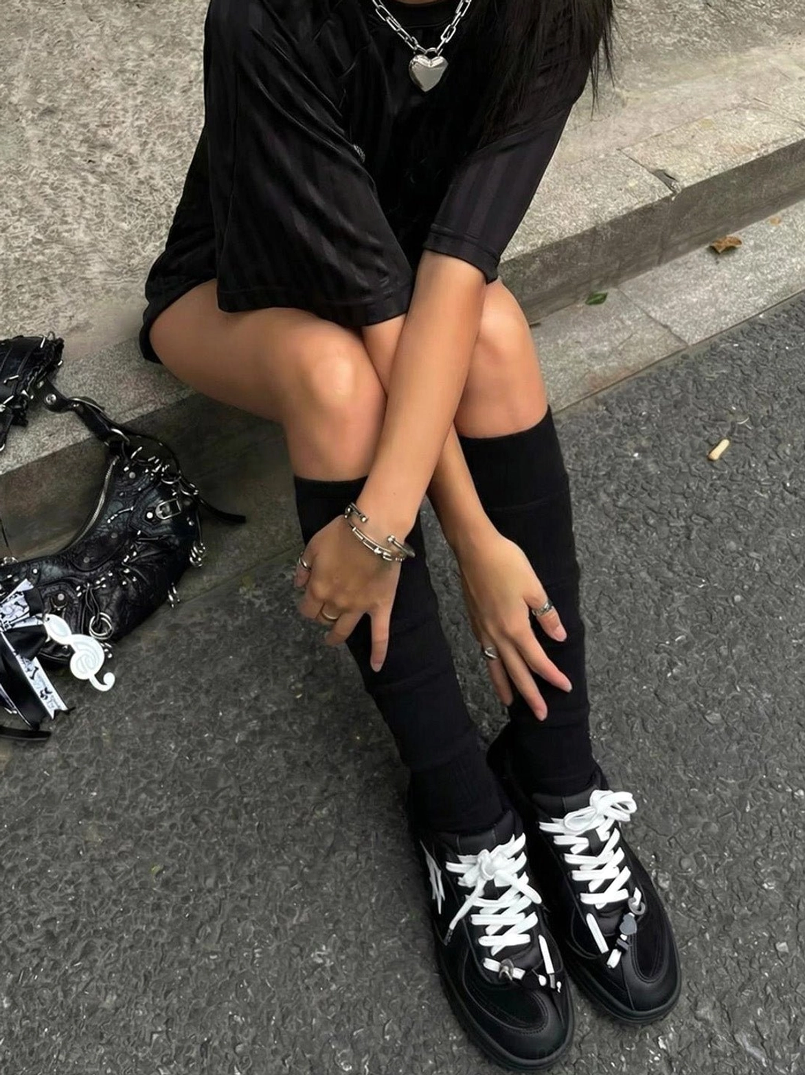Black solar star applique sneakers styled with knee-high socks and a punk-inspired handbag