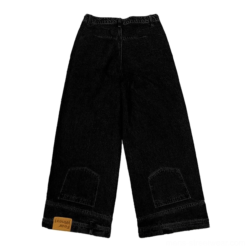 Flat lay view of solid black inside-out wide-leg denim jeans with square lower-leg pockets, layered cuffs, and monochrome finish