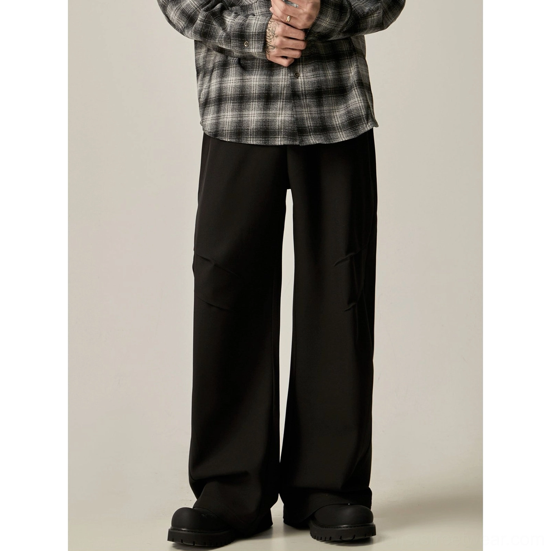 Solid black wide-leg trousers with smooth tailored fabric, relaxed streetwear silhouette, pleated cargo pockets, and chunky boots