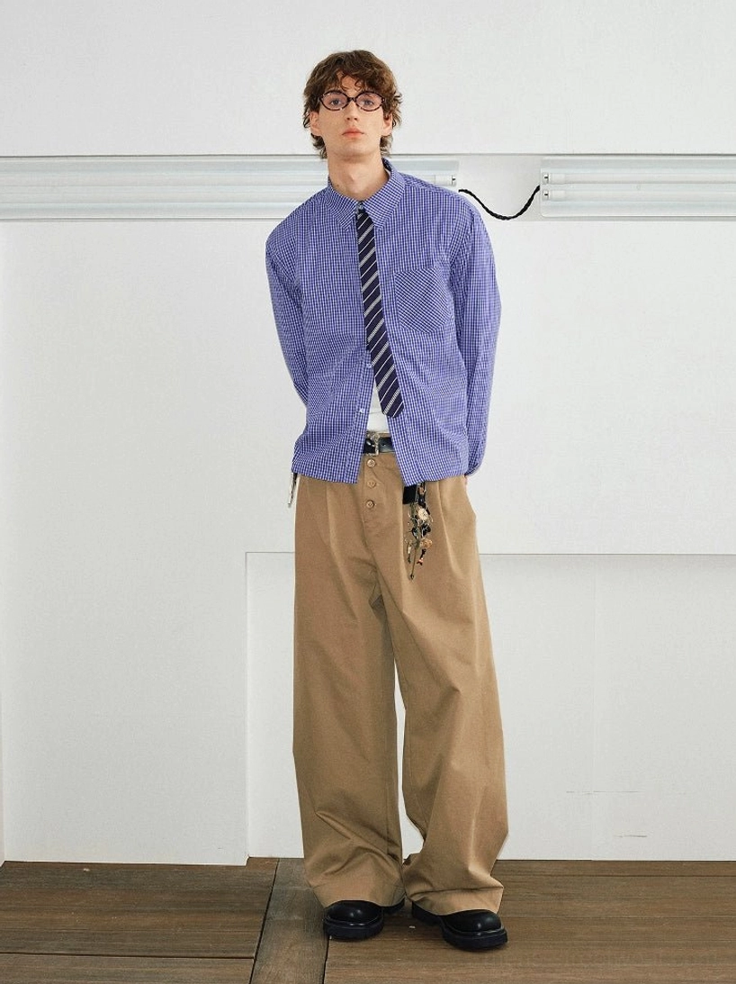 Male model wearing a solid purple long-sleeve shirt and striped tie with khaki wide-leg trousers