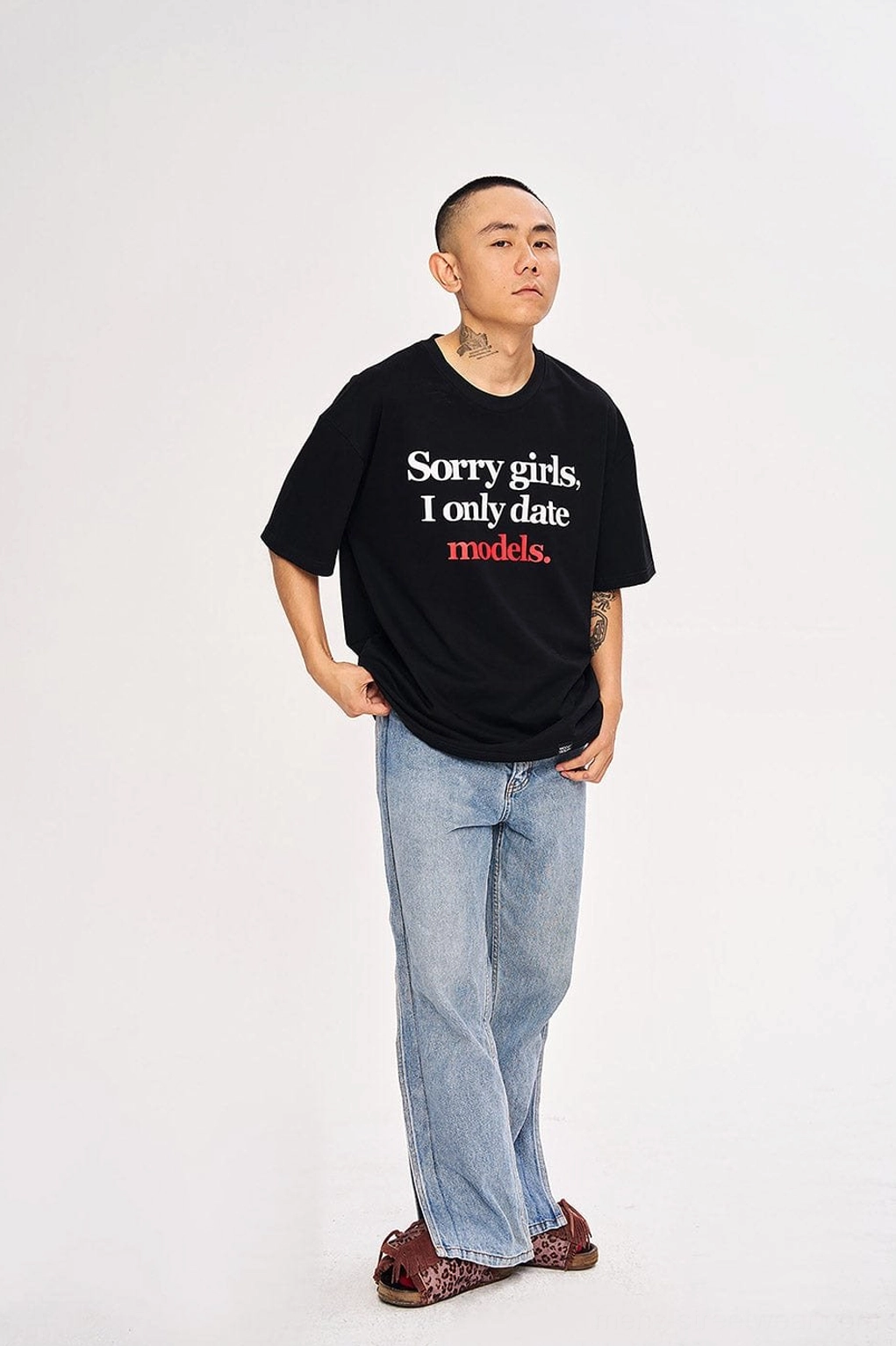 Black oversized graphic streetwear T-shirt styled with light blue jeans and casual slides