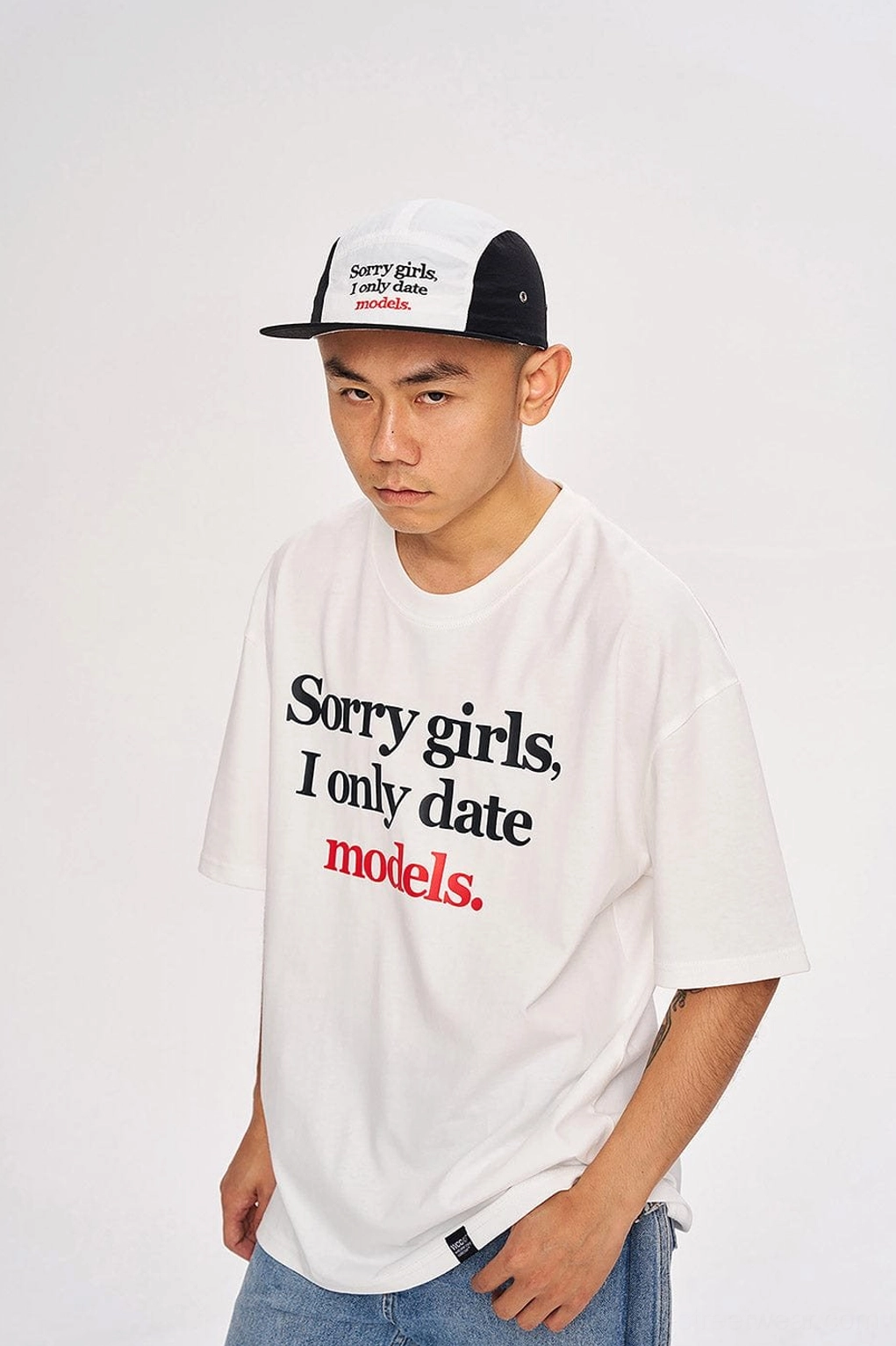 White oversized graphic slogan T-shirt photographed from a low angle with modern Korean streetwear styling