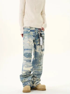 Men's blue acid wash grunge jeans with distressed ripped denim texture styled with a cream ribbed sweater and tan shearling boots