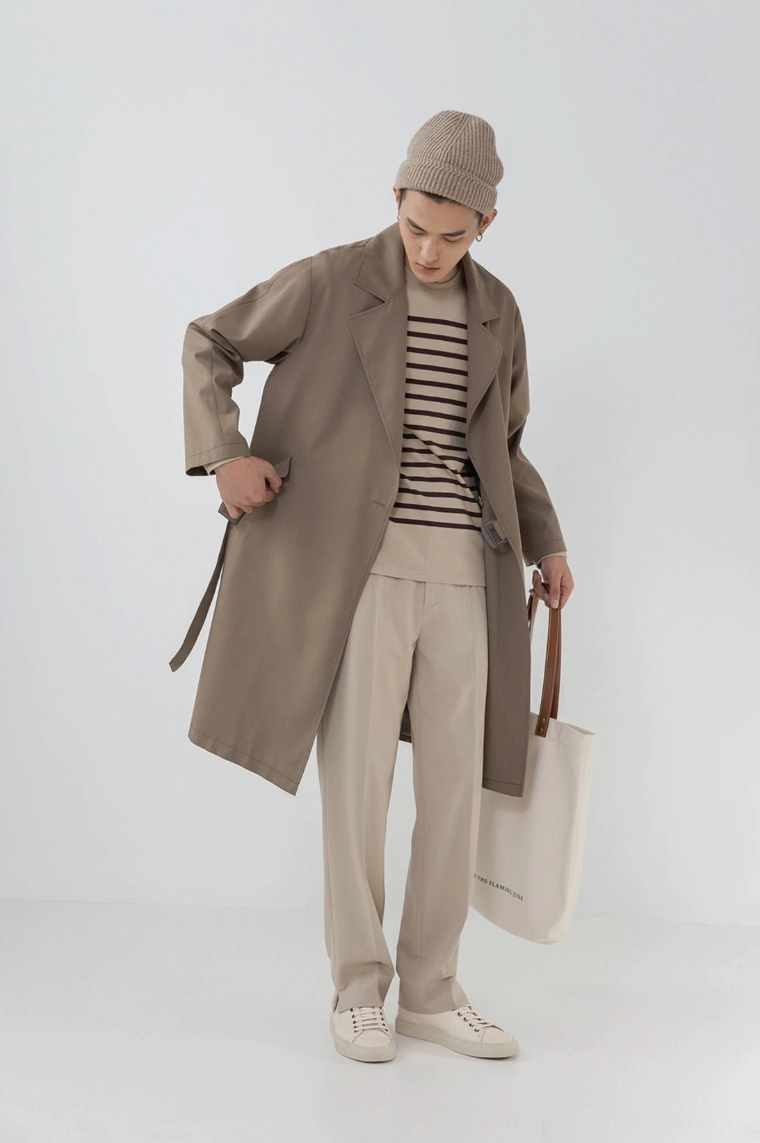 Layered outfit beige split hem pants long trench coat striped top knit beanie canvas bag full body