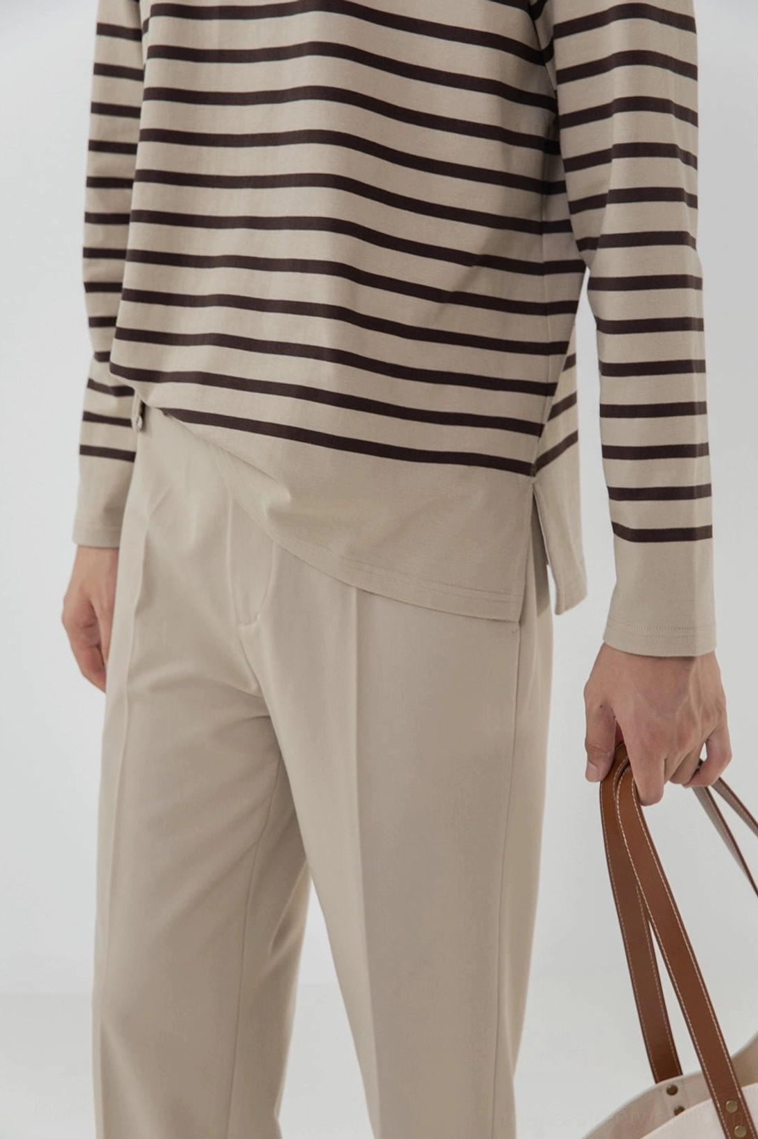 Close-up waist and thigh detail high-waisted tailored split hem pants leather tote bag styling