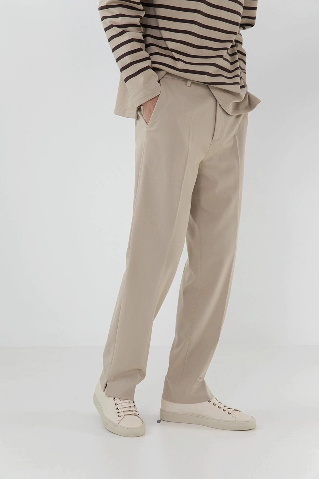 Beige split hem straight pants side view with striped knit top and white sneakers minimalist studio photography
