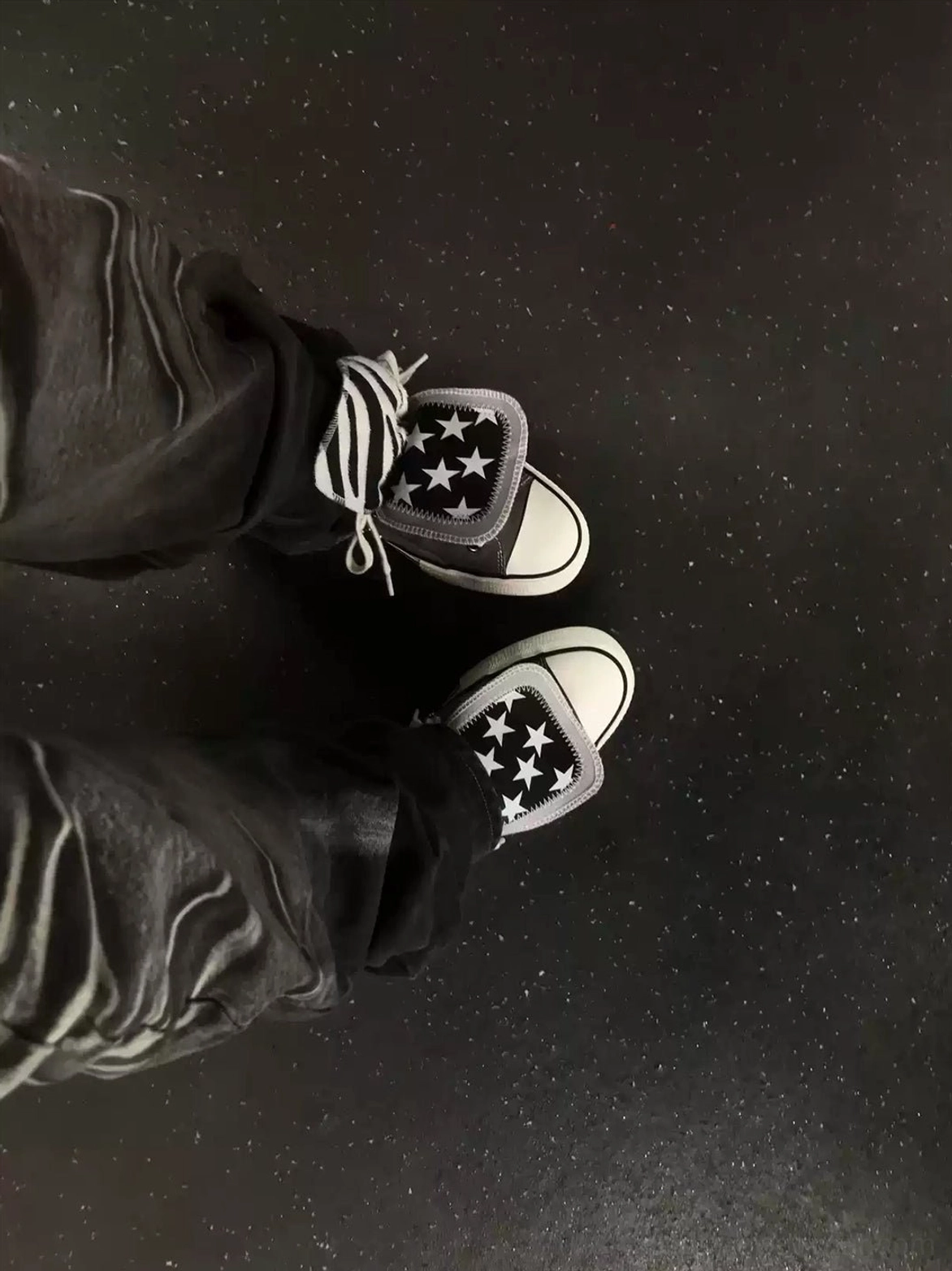 Model wearing star-pattern high-top canvas streetwear sneakers with dark cargo pants in a punk-inspired everyday outfit
