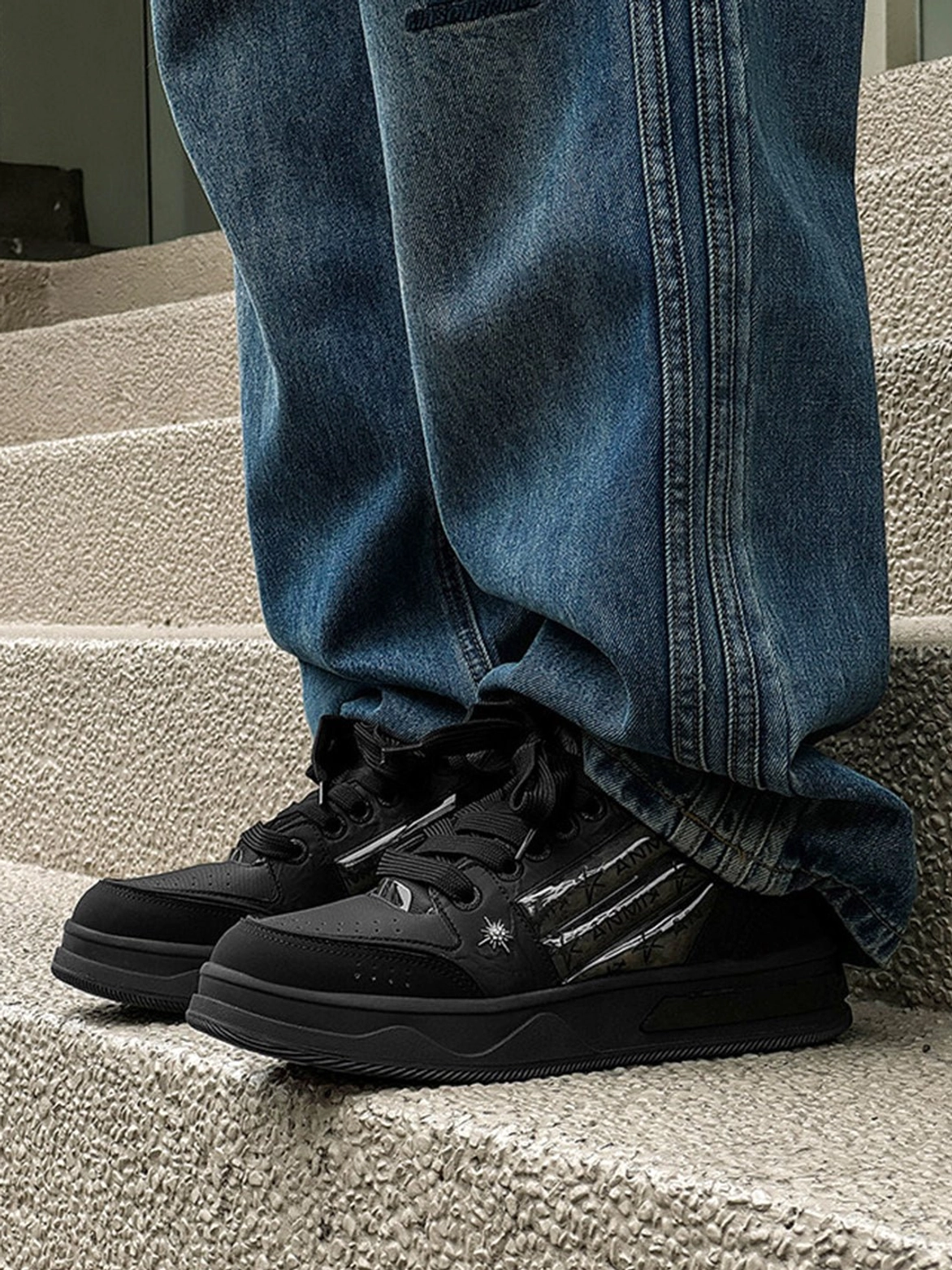 Star studded black gothic sneakers with silver side stripes and chunky platform soles styled with baggy blue denim jeans