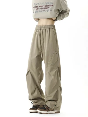 Khaki wide-leg cargo pants with elastic drawstring waist, side flap pockets, relaxed parachute silhouette, and adjustable cuffs in Korean streetwear style