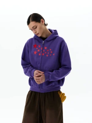 Purple Stellar Drift star print oversized zip-up hoodie with red chest stars, front view with loose brown trousers