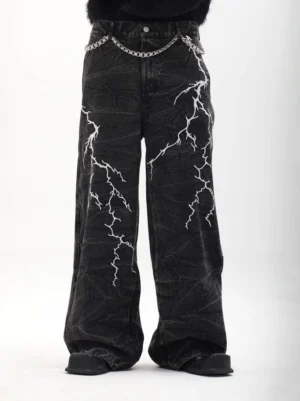Front view of black lightning graphic wide-leg denim jeans showing symmetrical white prints, textured wash, and button waistband