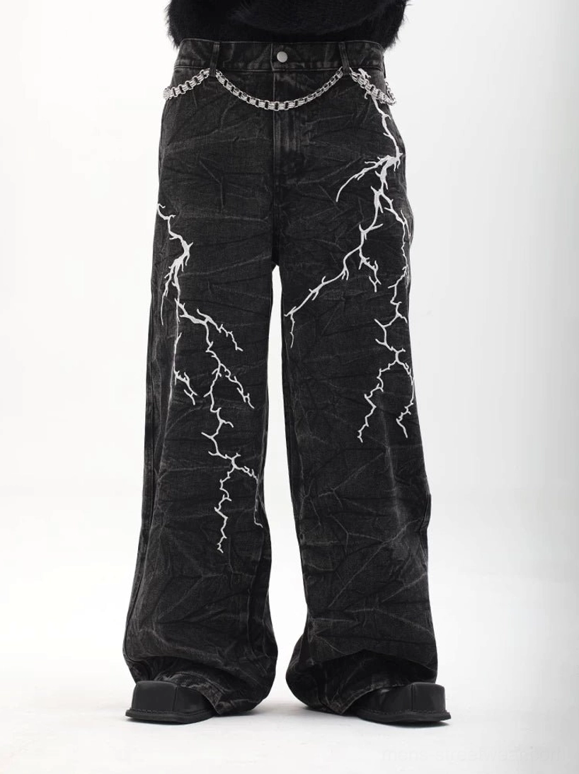 Front view of black lightning graphic wide-leg denim jeans showing symmetrical white prints, textured wash, and button waistband