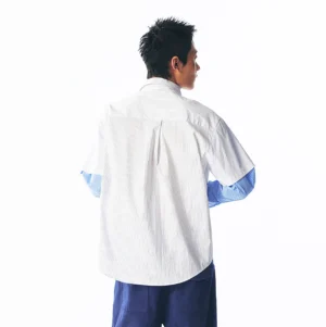 Back view of a layered strawberry graphic shirt showing the relaxed fit, back pleat detail, and blue striped sleeves