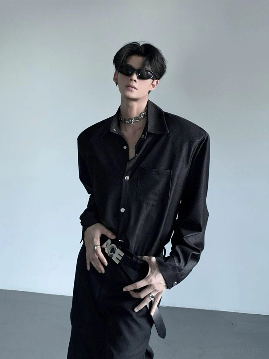 Close-up of men's black button-up shirt showing structured wide shoulders, neat button placket, matte woven fabric, and chest pocket