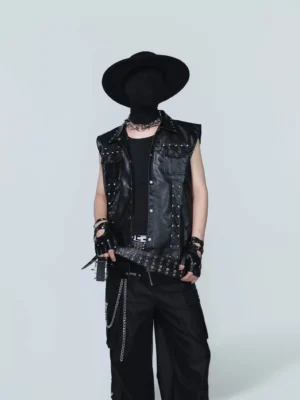 Front full-body view of a black studded PU leather punk vest with chest pockets, snap closure, metallic shoulder studs, and a sleeveless streetwear fit