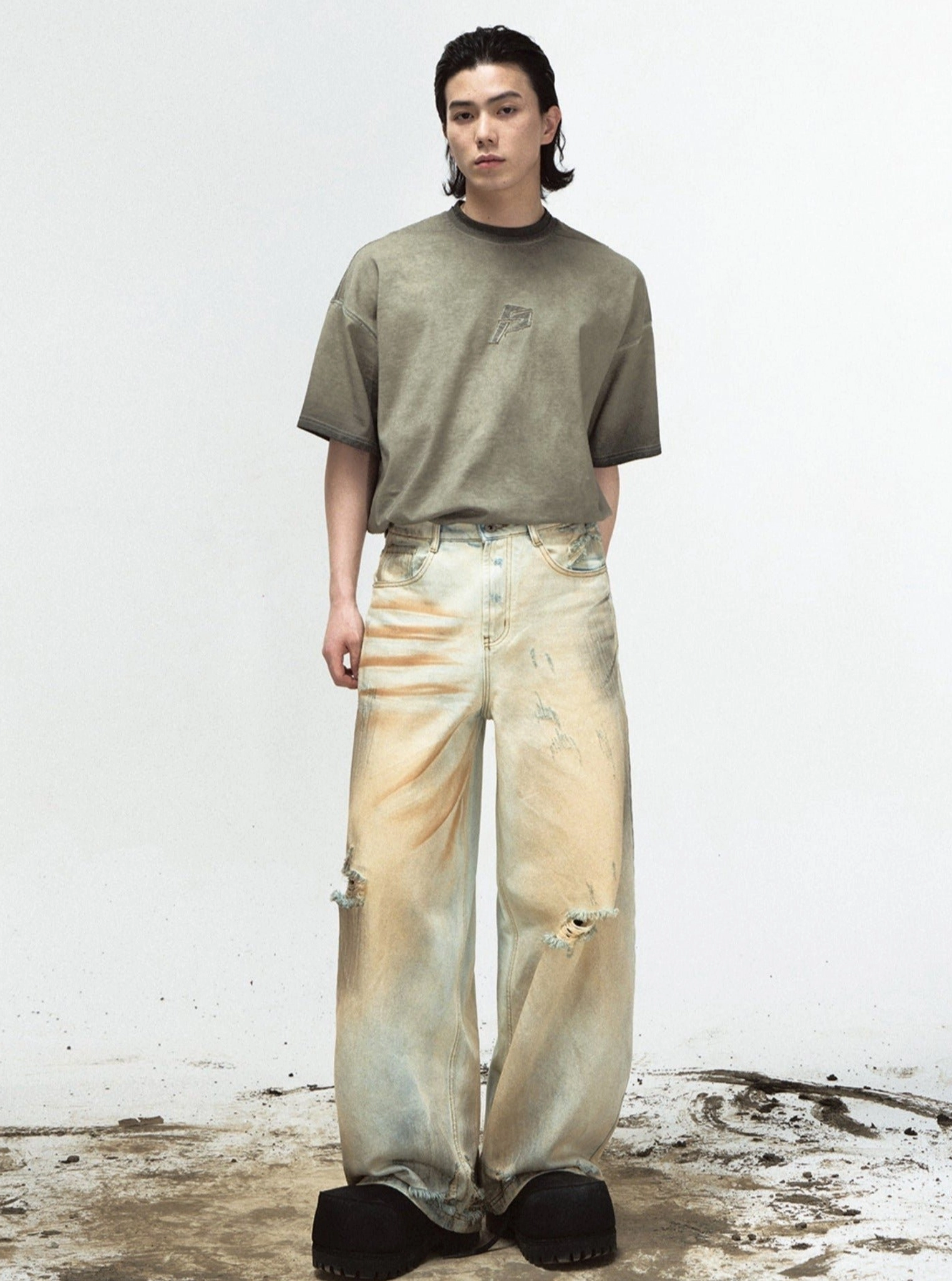 Front lower body view of sun-faded yellow ripped denim jeans paired with an oversized olive short-sleeve T-shirt