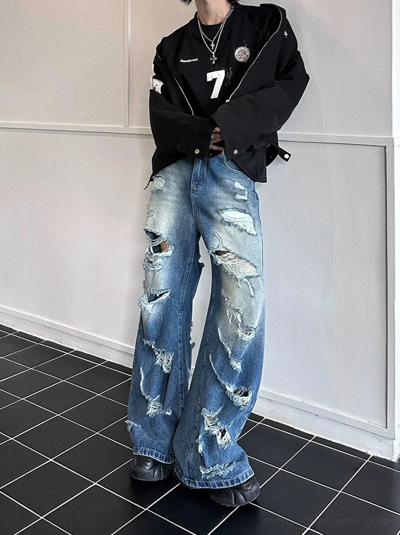 Front full-body view of super distressed wide-leg blue jeans styled with a black varsity jacket and chunky sneakers for Seoul streetwear