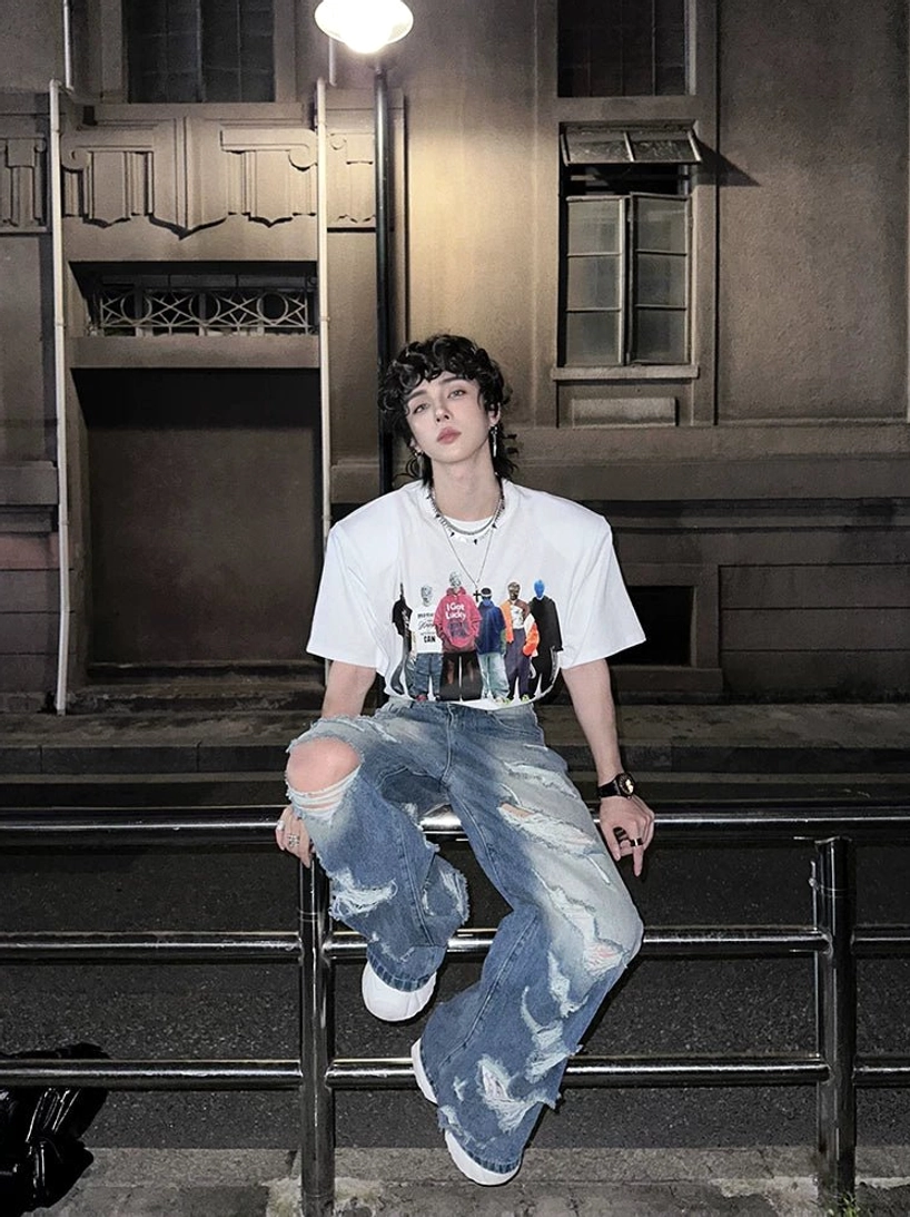 Relaxed wide-leg distressed blue jeans with knee rip and faded vintage wash styled with graphic tee and white sneakers