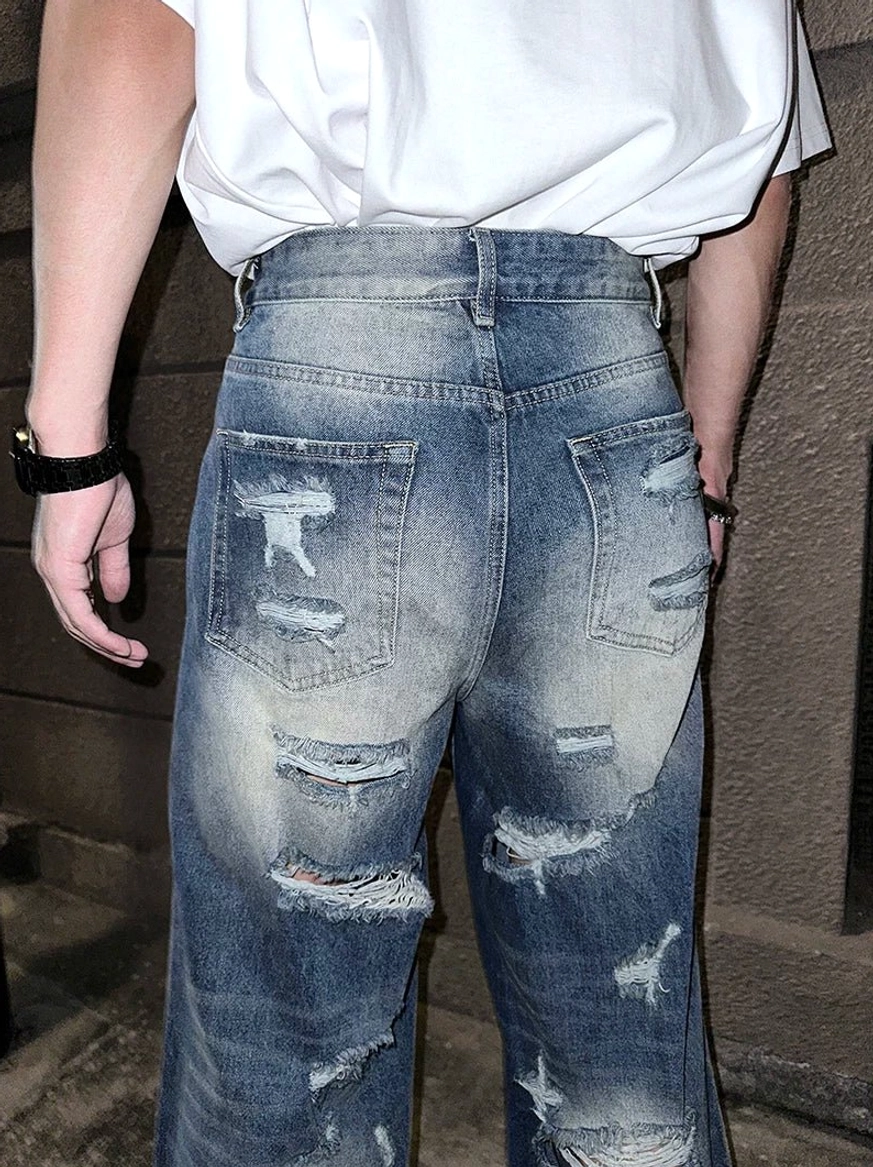 Loose-fit super distressed wide-leg blue denim jeans with allover frayed tears and long stacking silhouette