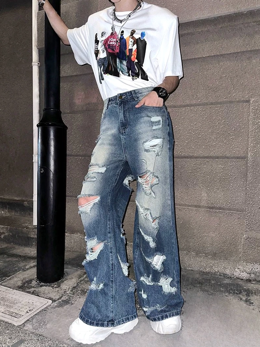 Side full-body view of loose super distressed wide-leg blue denim jeans with frayed tears and stacked leg silhouette