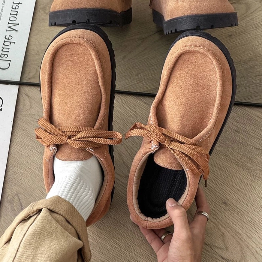 Tan brown square-toe suede lace-up casual shoes with tonal laces, thick black ridged outsole, white socks, and khaki trousers