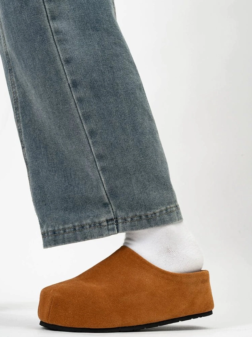 Tan brown suede platform clog worn with white socks and relaxed washed blue jeans in a minimalist streetwear outfit