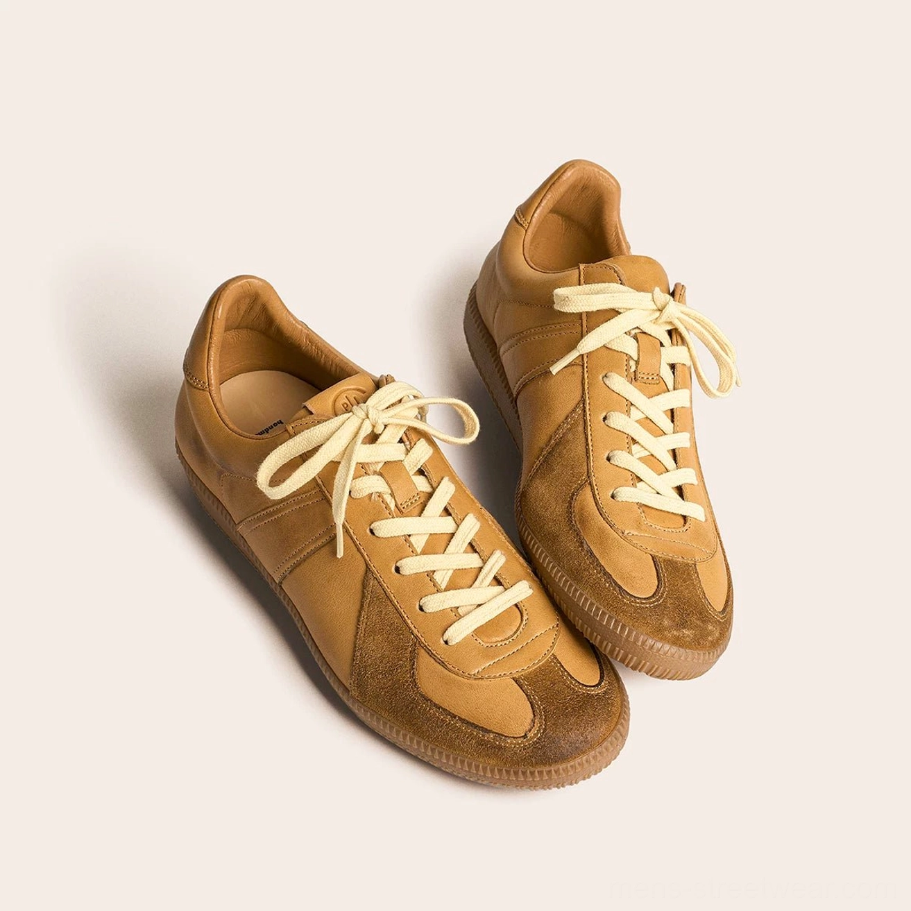 Pair of tan brown vintage leather sneakers with suede toe accents and off-white laces
