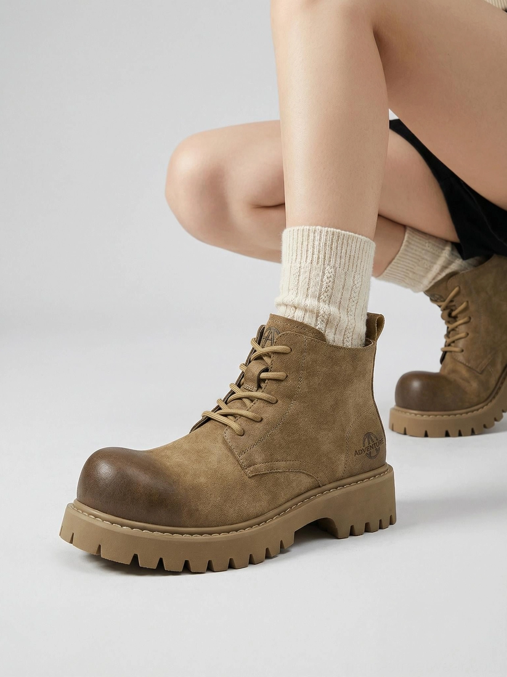 Tan lace-up lug-sole work boots shown from a three-quarter front angle with rounded toe and textured tread