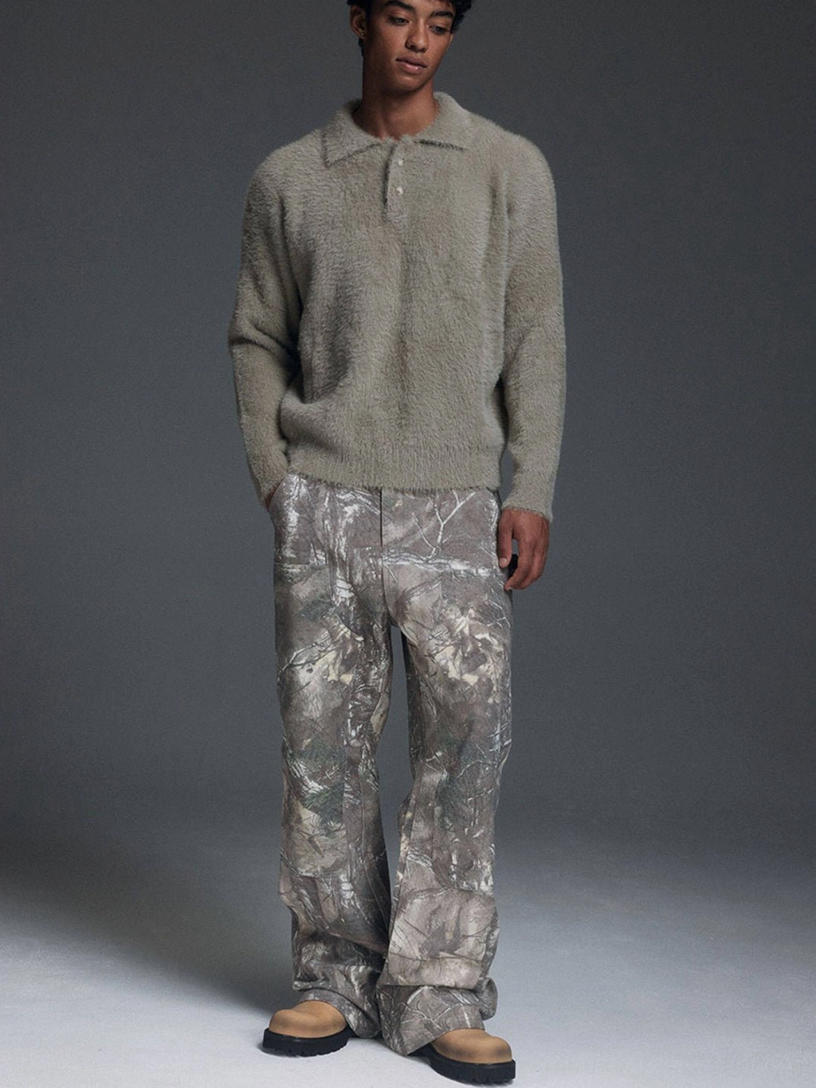 Full outfit styling with tan leather lug-sole derby shoes, taupe knit polo, and wide-leg camouflage pants