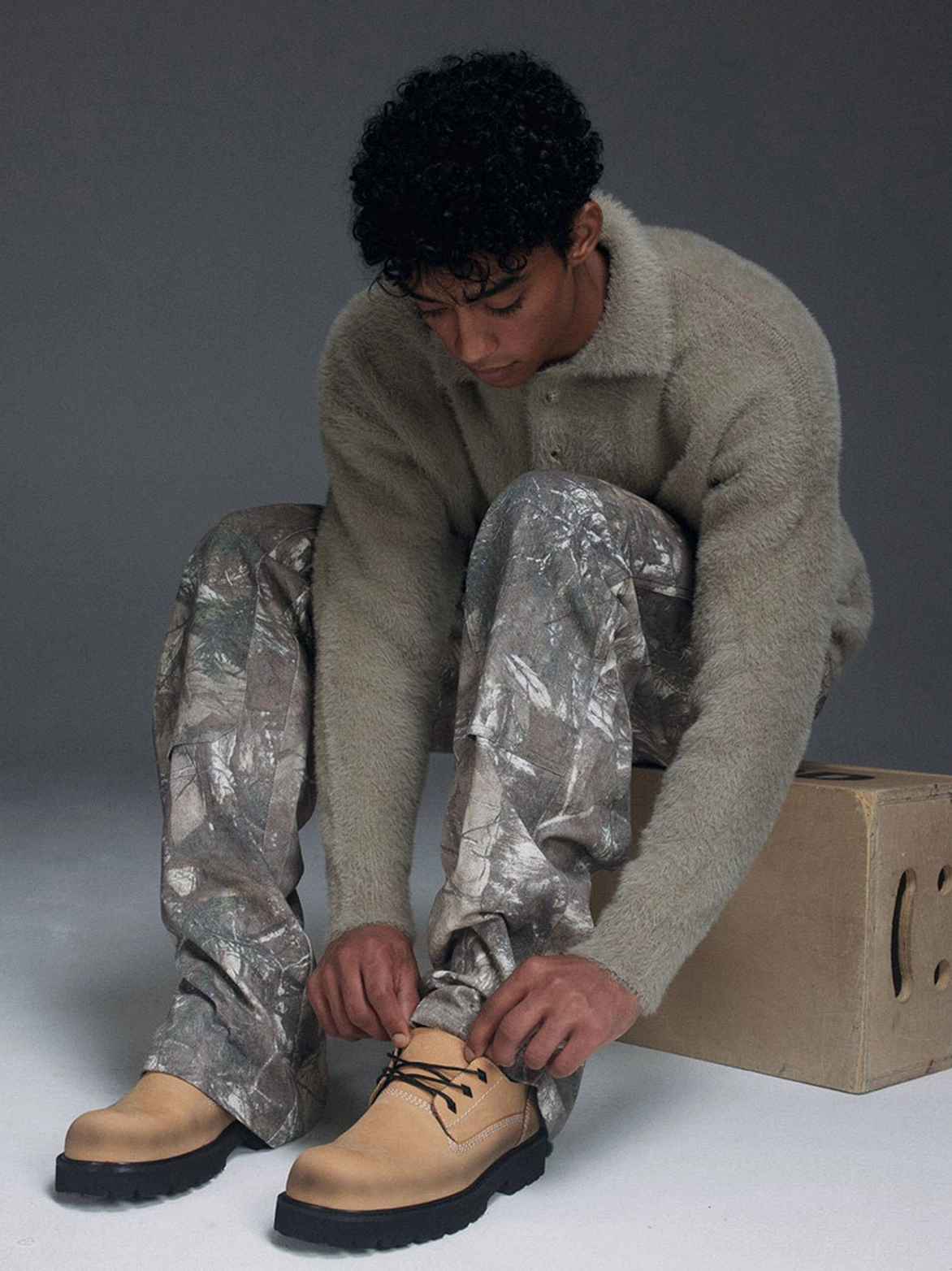 Three-quarter view of tan leather workwear derby shoes worn with camouflage pants and relaxed streetwear styling
