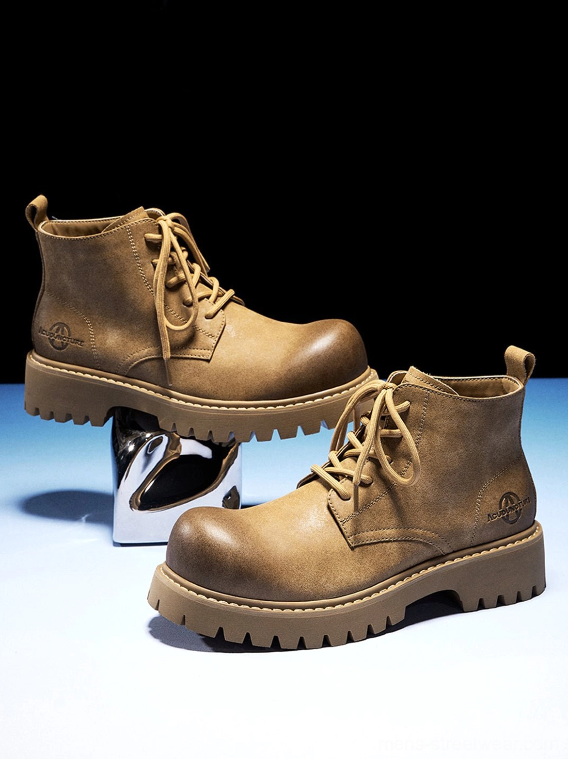 Tan synthetic leather lug-sole work boots displayed against a dark studio background showing side and front details