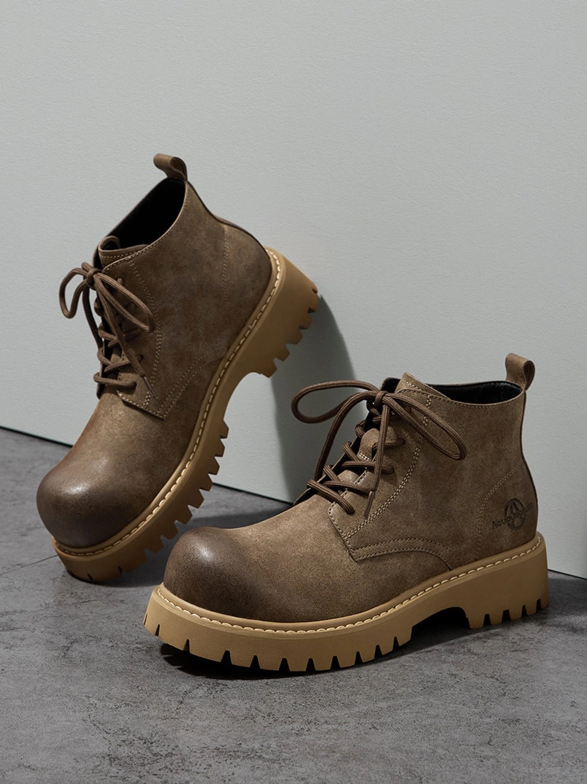 Tan utility streetwear boots shown as a durable-looking lace-up ankle silhouette with textured lug tread