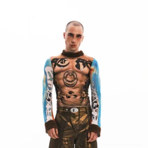 Front full-body view of a model wearing a tattoo illusion sheer mesh long sleeve top with blue graphic sleeves and brown textured trims