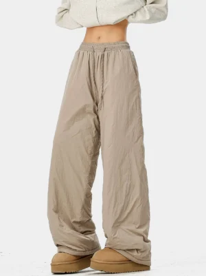 Taupe beige crinkled nylon convertible pants full front lower body view showing relaxed wide-leg silhouette and elastic drawstring waist