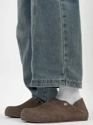 Taupe brown fleece-lined suede clogs worn with white socks and blue jeans, front view of casual streetwear slip-on footwear